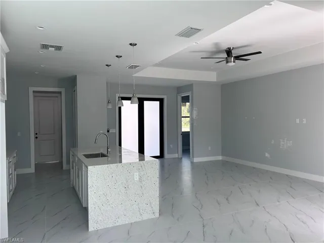 Kitchen with ceiling fan, sink, pendant lighting, a center island with sink, and white cabinets