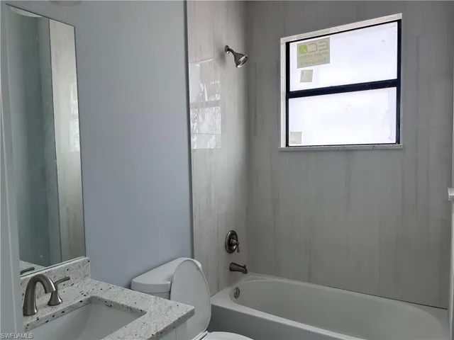Full bathroom with tiled shower / bath combo, toilet, and vanity