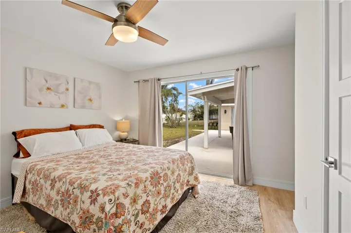 Bedroom featuring light wood-type flooring, access to outside, baseboards, and ceiling fan