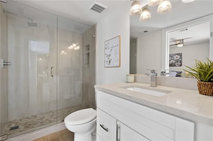 Full bath featuring toilet, a shower stall, and visible vents