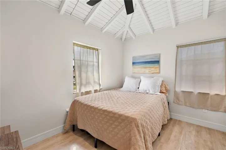 Bedroom featuring vaulted ceiling with beams, ceiling fan, wood finished floors, and baseboards