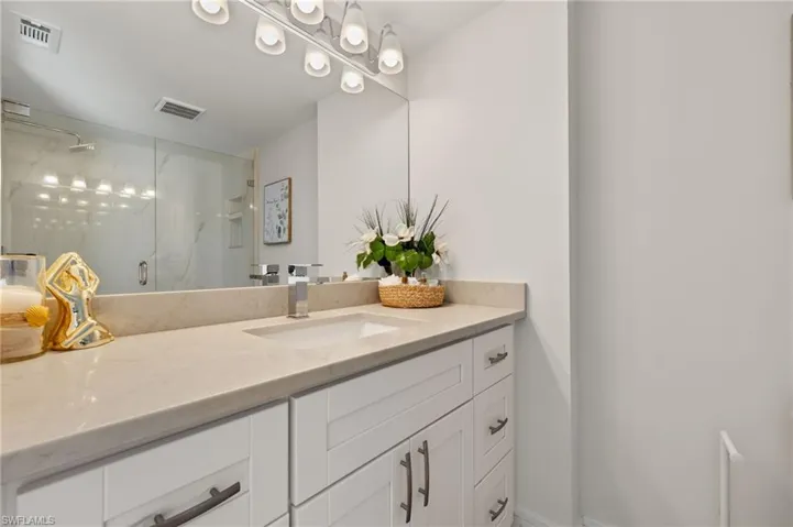 Bathroom featuring visible vents, vanity, and a marble finish shower
