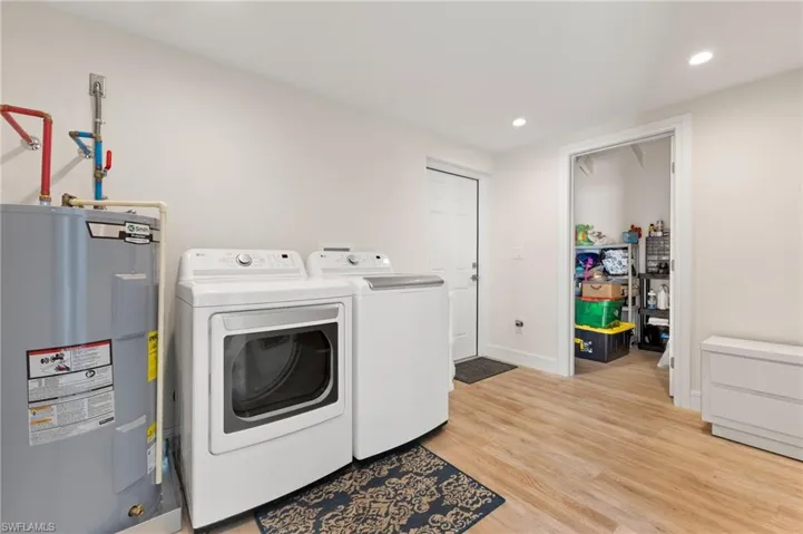 Clothes washing area featuring laundry area, light wood finished floors, independent washer and dryer, water heater, and recessed lighting