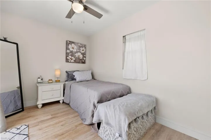 Bedroom with ceiling fan, light wood finished floors, and baseboards