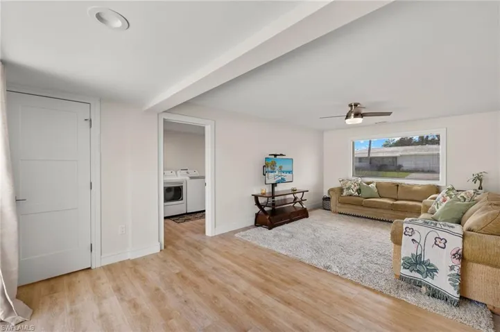 Living area featuring light wood-type flooring, ceiling fan, baseboards, and separate washer and dryer