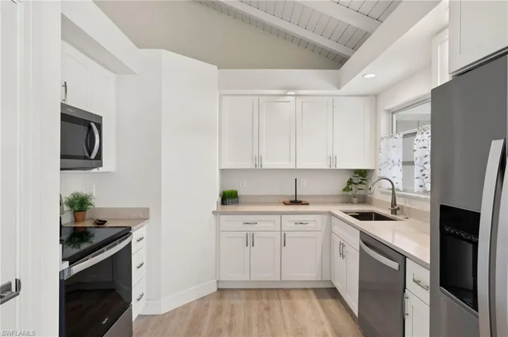 Kitchen with light countertops, appliances with stainless steel finishes, a sink, and white cabinetry