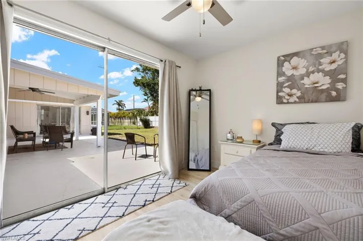 Bedroom with light wood-type flooring, access to outside, baseboards, and ceiling fan