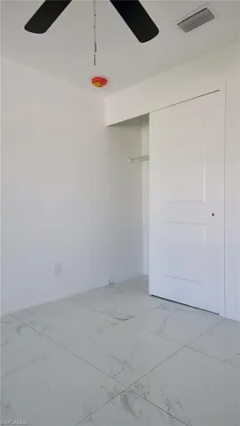 Spare room featuring marble finish floor, baseboards, visible vents, and a ceiling fan