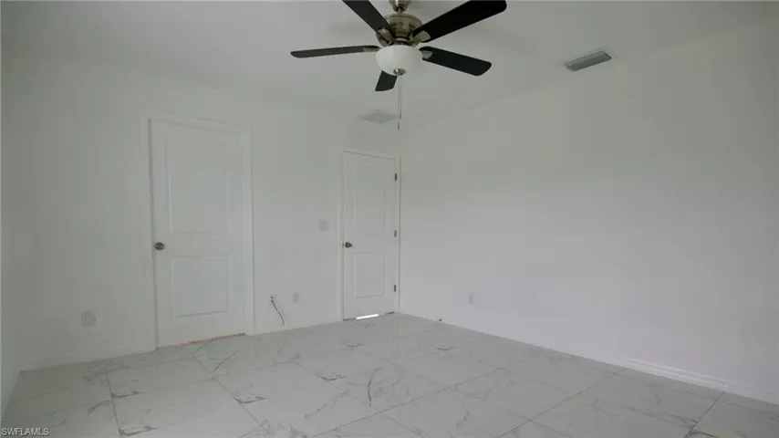 Unfurnished room featuring marble finish floor, baseboards, visible vents, and ceiling fan