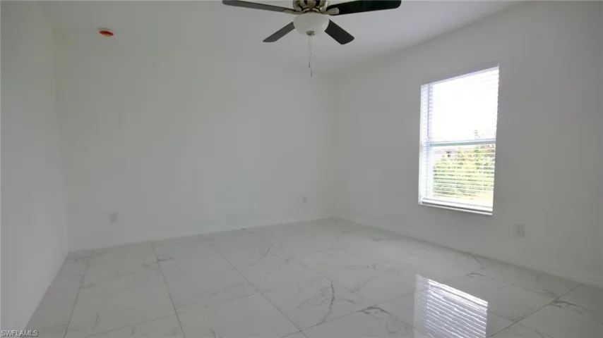 Spare room with baseboards, marble finish floor, and ceiling fan