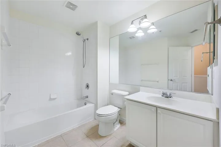 Full bathroom featuring vanity, tiled shower / bath combo, toilet, and tile patterned flooring
