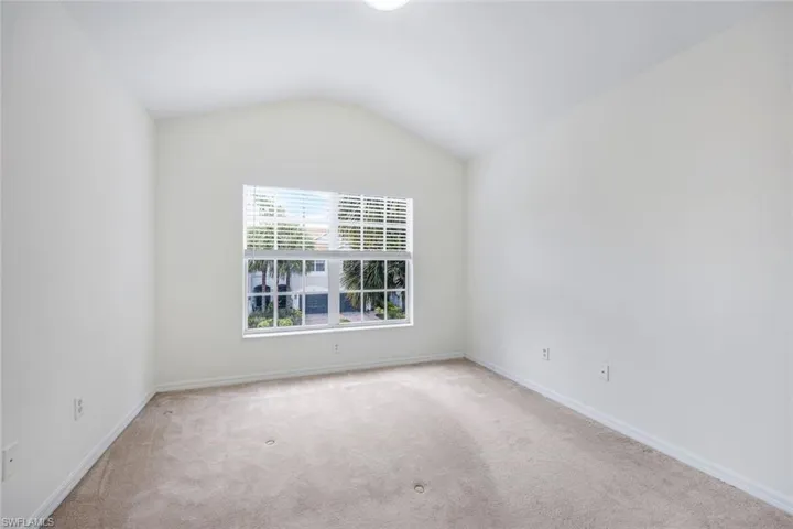 Carpeted empty room featuring vaulted ceiling