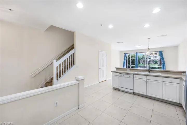 Kitchen featuring white cabinets, light tile patterned floors, white dishwasher, and sink