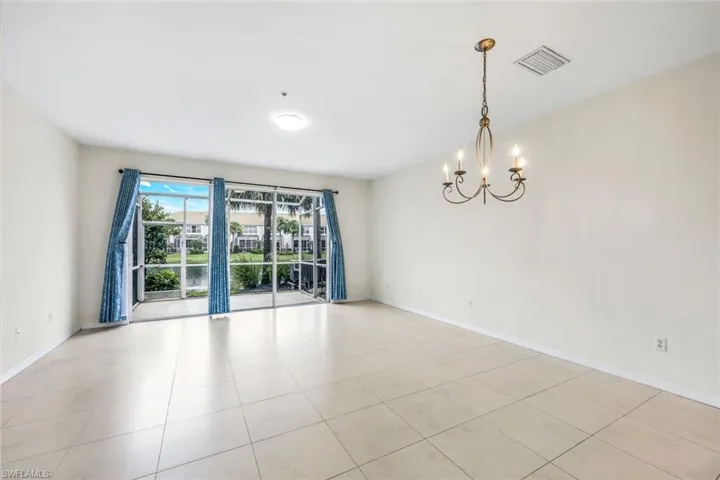 Tiled spare room featuring an inviting chandelier