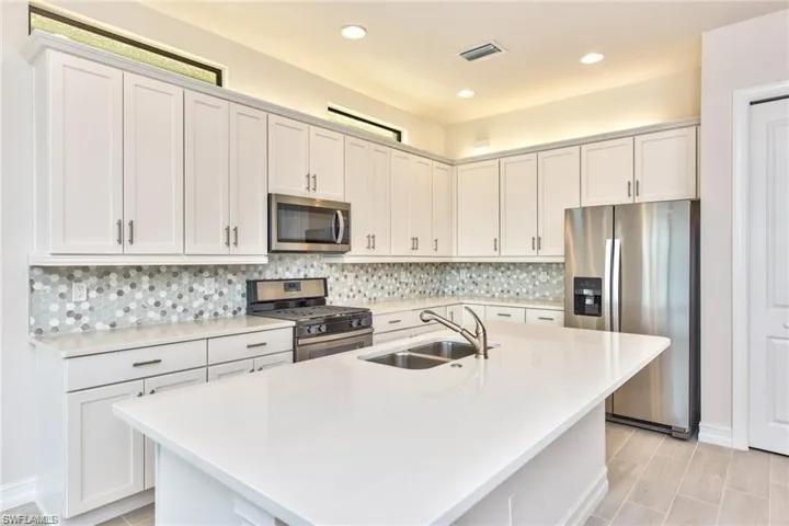 Kitchen with visible vents, a sink, decorative backsplash, light countertops, and stainless steel appliances