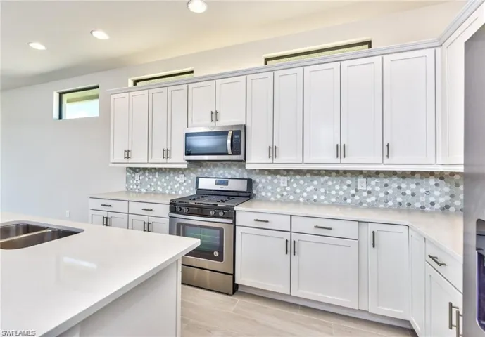 Kitchen featuring recessed lighting, backsplash, appliances with stainless steel finishes, and light countertops