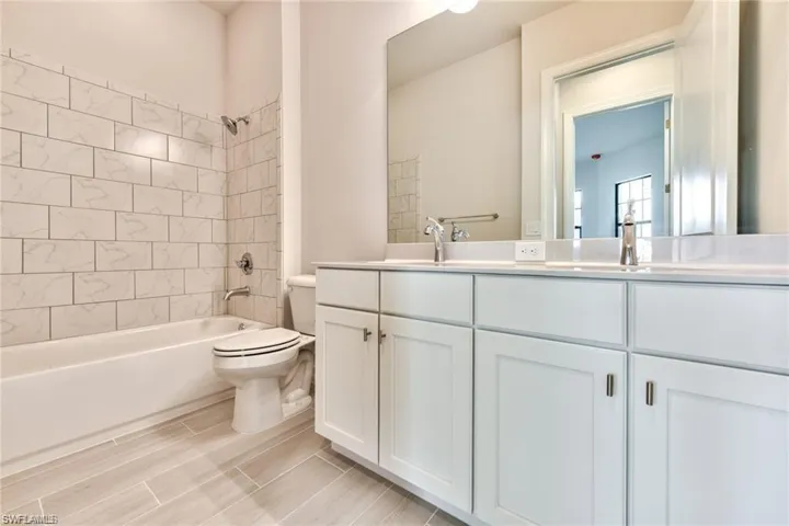 Full bath with double vanity, shower / bathing tub combination, toilet, and a sink