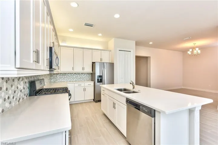 Kitchen featuring visible vents, a sink, backsplash, appliances with stainless steel finishes, and light countertops
