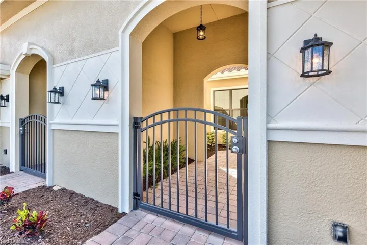 View of exterior entry with a private gate and stucco siding