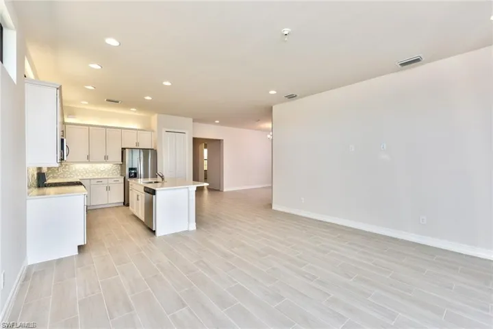 Kitchen featuring a kitchen island with sink, backsplash, open floor plan, stainless steel appliances, and light countertops