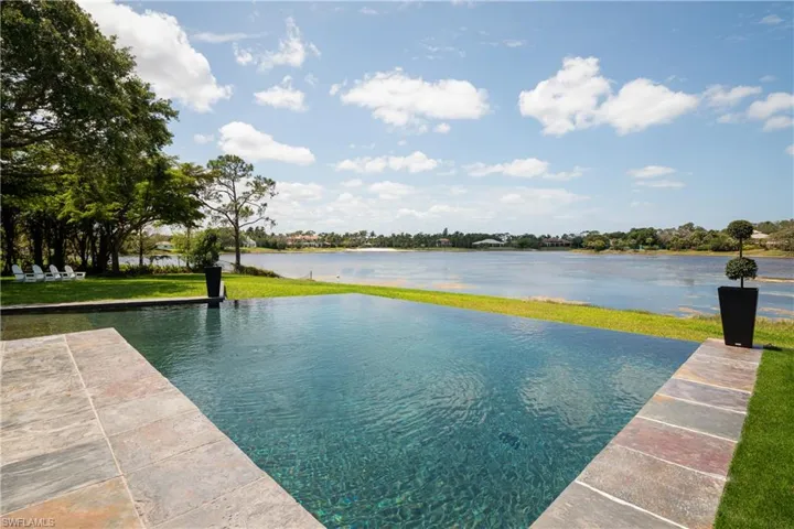 View of swimming pool with a lawn and a water view