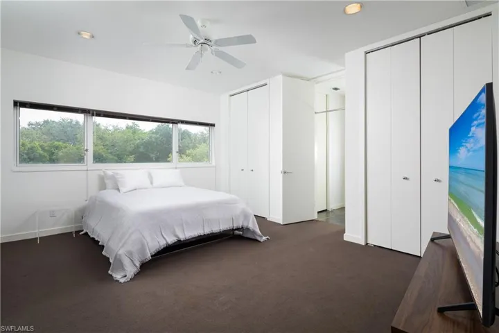 Bedroom featuring dark carpet, ceiling fan, and multiple closets