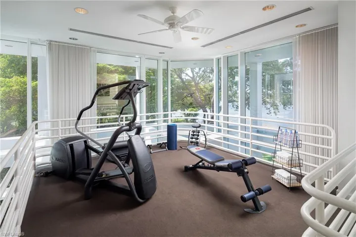 Exercise room with floor to ceiling windows, ceiling fan, and a healthy amount of sunlight