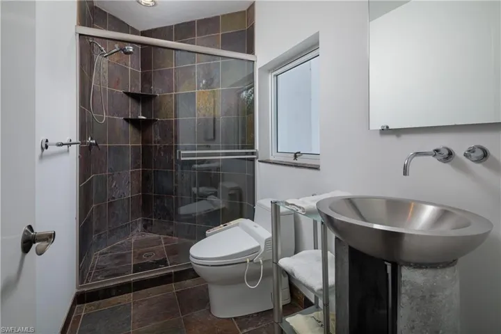 Bathroom with toilet, an enclosed shower, and sink