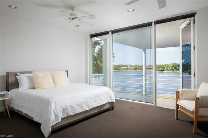 Carpeted bedroom featuring ceiling fan, expansive windows, and access to exterior