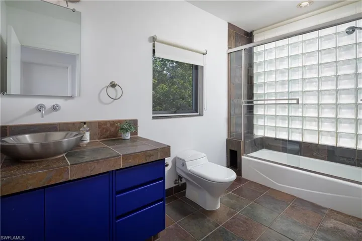 Full bathroom with shower / bath combination with glass door, vanity, and toilet