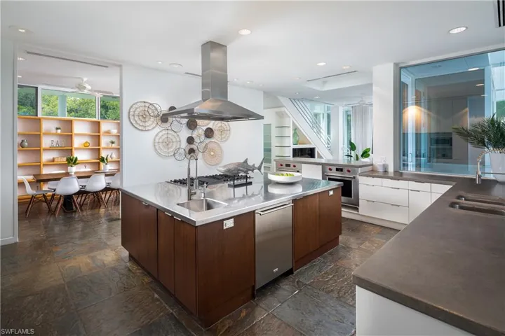Kitchen with dark brown cabinetry, island range hood, sink, and stainless steel appliances
