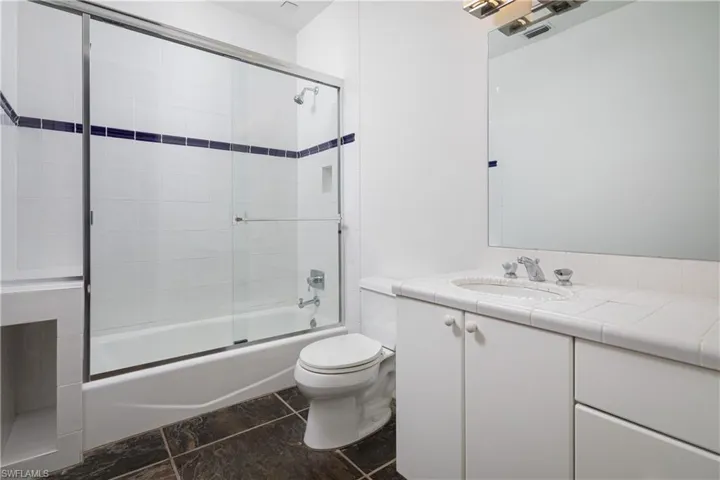 Full bathroom with vanity, toilet, and enclosed tub / shower combo