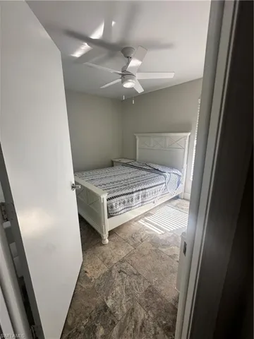 Unfurnished bedroom featuring stone tile flooring and ceiling fan