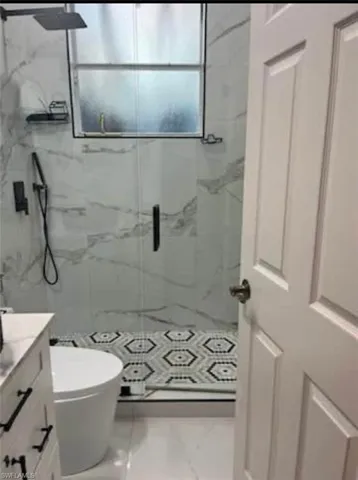 Bathroom featuring vanity and a marble finish shower
