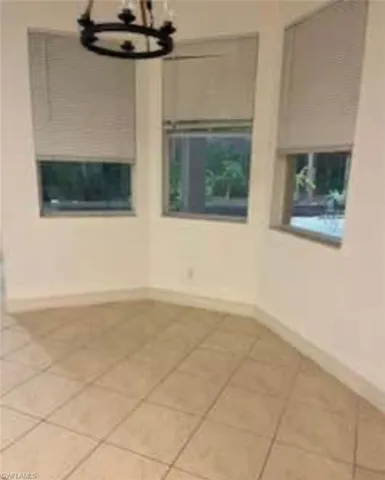 Spare room with a chandelier and light tile patterned floors