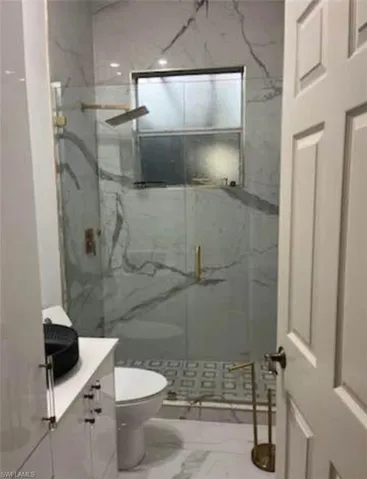 Full bathroom with vanity, a marble finish shower, and marble look tiles