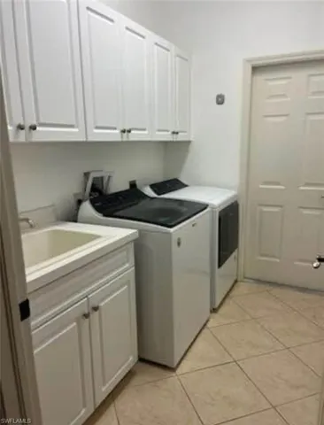 Laundry area with cabinet space, light tile patterned flooring, and washing machine and clothes dryer