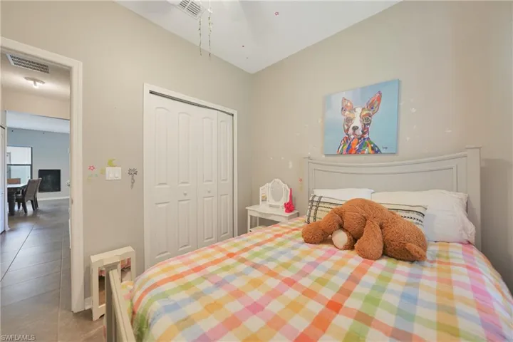 Tiled bedroom with a closet, visible vents, and a ceiling fan