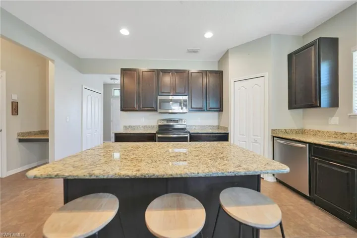 Kitchen featuring a center island, dark brown cabinets, a breakfast bar, and stainless steel appliances