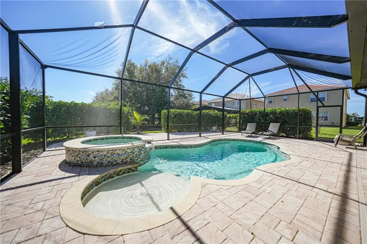 View of pool featuring a pool with connected hot tub, glass enclosure, and a patio area