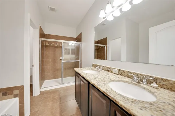 Full bath featuring visible vents, a sink, a stall shower, and tile patterned floors