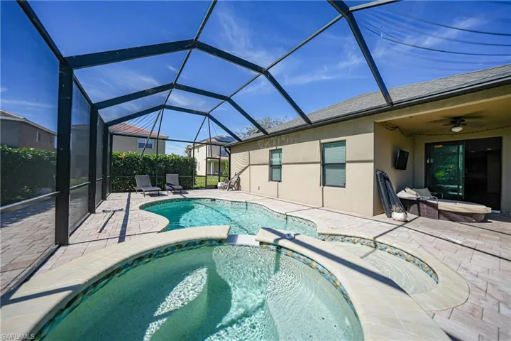 View of swimming pool featuring a lanai, a pool with connected hot tub, a ceiling fan, and a patio area