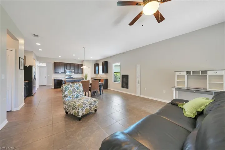 Tiled living area featuring baseboards, ceiling fan, and recessed lighting