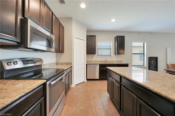 Kitchen featuring appliances with stainless steel finishes, light tile patterned floors, visible vents, recessed lighting, and dark brown cabinets