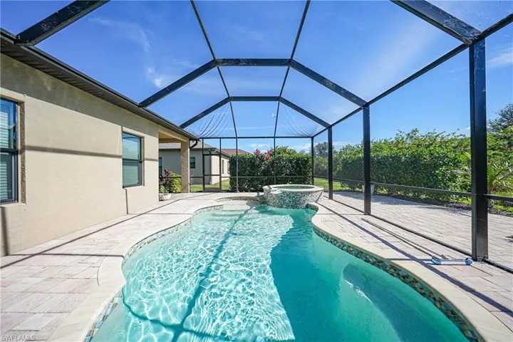 View of pool with a pool with connected hot tub, glass enclosure, and a patio area