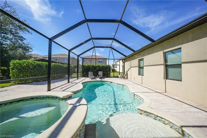 View of swimming pool with a pool with connected hot tub, glass enclosure, and a patio area