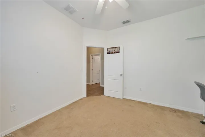Spare room featuring a ceiling fan, baseboards, light colored carpet, and visible vents