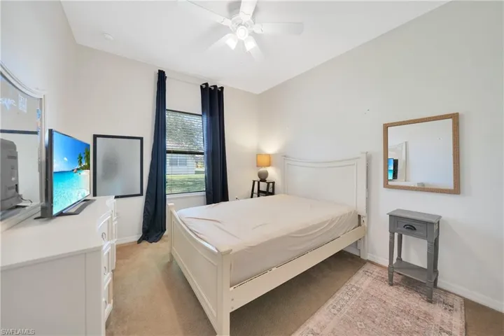 Bedroom featuring light carpet, baseboards, and ceiling fan