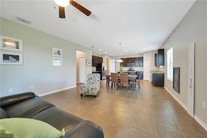 Tiled living room featuring a ceiling fan, recessed lighting, baseboards, and visible vents