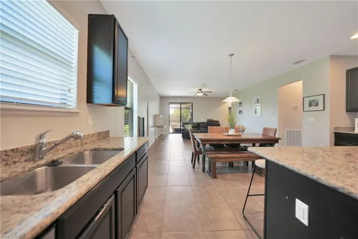 Kitchen featuring light tile patterned flooring, a sink, open floor plan, visible vents, and ceiling fan